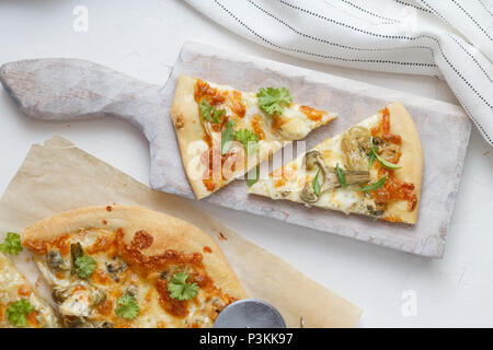 Deux morceaux de pizza au fromage avec des artichauts et roquette Banque D'Images