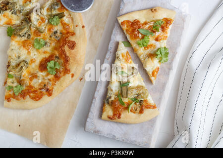 Pizza au fromage avec des artichauts et roquette on cutting board Banque D'Images