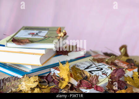 Les manuels scolaires, livres sur table avec des feuilles aux couleurs automnales, contre un fond violet avec copie Espace Concept de de commencer l'école, le retour à l'école, de l'éducation Banque D'Images