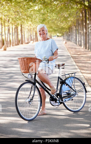 Portrait Of Smiling Senior Woman sitting on Country Road Banque D'Images