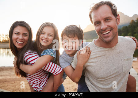 Portrait de parents Donner aux enfants Piggyback Ride In Countryside Banque D'Images
