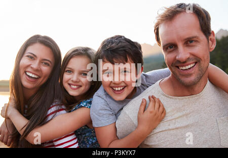 Portrait de parents Donner aux enfants Piggyback Ride In Countryside Banque D'Images