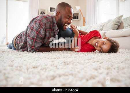 Père Fils de chatouillement comme ils jouent ensemble dans le salon de jeu Banque D'Images