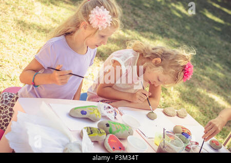 Jolie petite blonde s'amuse avec la peinture des pierres Banque D'Images