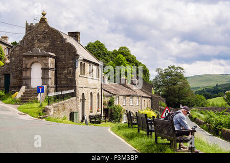 Walker se reposant sur un banc par Muker Institut littéraire dans le Yorkshire Dales National Park Village de Muker Swaledale North Yorkshire Angleterre Royaume-uni Grande-Bretagne Banque D'Images