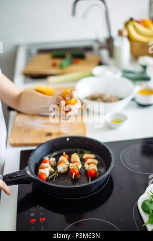 Portrait de jeune femme au foyer heureuse la viande de poulet à frire pour le dîner Banque D'Images