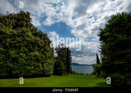 Belle vue sur jardin verdoyant avec de grands arbres et d'oiseaux et pittoresque ciel nuageux à l'île Isola Bella, dans le lac Lago di Maggiore. L'Italie, le printemps. Banque D'Images