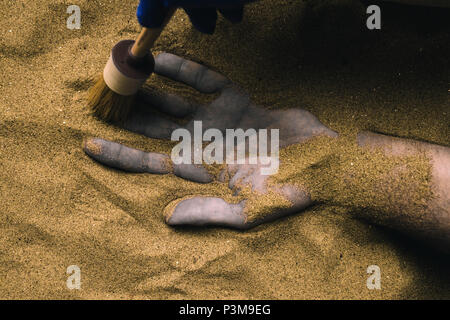 Expert en médecine légale à la découverte de corps mort enterré dans le sable du désert. Image conceptuelle pour la police enquête sur un meurtre dans une affaire de scène de crime. Banque D'Images