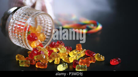 Marmelade dans un vase sur la table. Bonbons dans un bol sur un fond noir. Jelly multicolore des bonbons pour les enfants. Banque D'Images