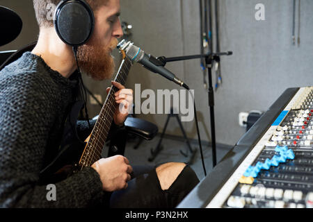 Musicien jouant et chantant en studio Banque D'Images