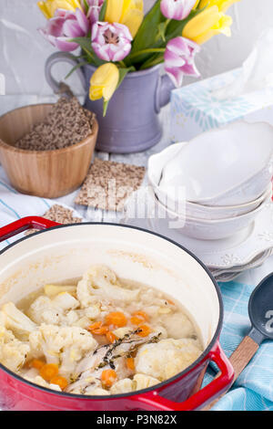 Le chou-fleur cuit dans une fonte rouge. Une serviette bleue. Espace libre pour le texte. Dîner en famille. Aliments diététiques. Banque D'Images