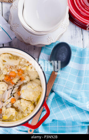 Le chou-fleur cuit dans une fonte rouge. Une serviette bleue. Espace libre pour le texte. Dîner en famille. Aliments diététiques. Banque D'Images