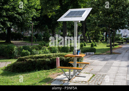 Nis, Serbie - 16 juin 2018 : Mobile panneau solaire sur le banc dans un parc public pour la charge de la batterie du téléphone cellulaire sur l'énergie verte. Moderne et l'écologie Banque D'Images