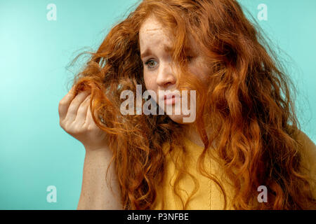 Contrarié et femme avec son expression visage cheveux secs endommagés fond bleu Banque D'Images