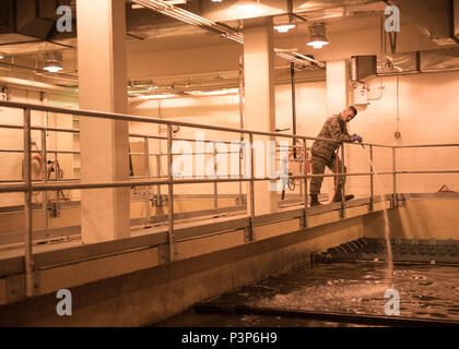 U.S. Air Force Troy Navigant de première classe, un Moncrief 354e Escadron de génie civil, de l'apprenti d'eaux usées se lave les murs d'une piscine souterraine du bassin de sédimentation à l'Eielson Air Force Base, Alaska, usine de traitement des eaux usées, 14 juillet 2016. La plupart de l'usine est souterraine, gardant les processus critiques à partir de la météo qui peut descendre jusqu'à 50 degrés en dessous de zéro à l'intérieur de l'Alaska. (U.S. Photo de l'Armée de l'air par le sergent. Shawn Nickel) Banque D'Images