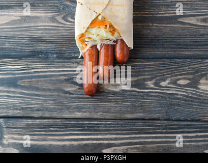 Saucisse fumée dans le pain pita sur un fond de bois foncé.photo with copy space Banque D'Images