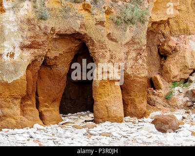 Petite grotte dans les strates de carstone Old Hunstanton cliffs demonstrsating les effets de l'érosion marine. Banque D'Images