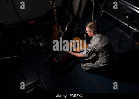 Jamie Navigant de première classe Teachenor, U.S. Air Force Academy et bande bleu sauvages Pays chanteur, enlève sa guitare acoustique de son cas à la base aérienne Peterson, au Colorado, le 20 juillet 2016. Teachenor effectue la plupart de ses chansons tout en jouant le piano ou la guitare. (U.S. Air Force photo par un membre de la 1re classe Dennis Hoffman) Banque D'Images