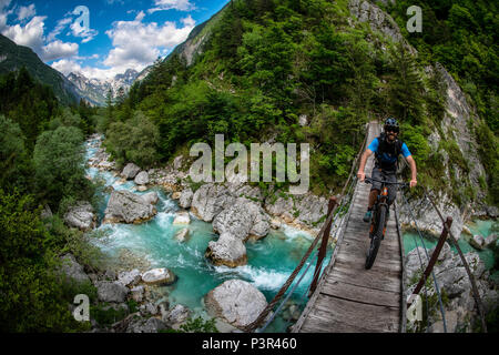 Une des promenades en vélo de montagne à travers un pont de bois sur la rivière Soca en Slovénie, l'Europe. Banque D'Images