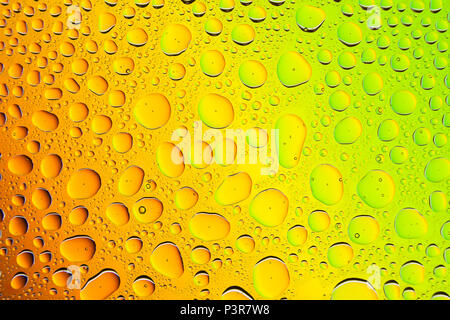 Gros plan d'une goutte d'eau sur un carton jaune, orange, green background, couvertes de gouttes d'eau -la condensation. Banque D'Images