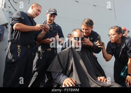 Golfe d'ADEN (16 juillet 2016) Gunner's Mate 2e classe Coren Demastus rasages Chef Gunner's Mate Jose Leon's cheveux pendant une activité de financement pour le premier maître mess des officiers sur le pont du destroyer USS-missiles Mason (DDG 87). Mason, déployés dans le cadre du groupe aéronaval d'Eisenhower, appuie les opérations de sécurité maritime et les efforts de coopération en matière de sécurité dans le théâtre dans la 5e flotte américaine zone d'opérations. (U.S. Photo par Marine Fire Controlman Tahriqa 2e classe Fareed/libérés) Banque D'Images