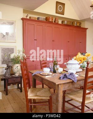 Rush assis chaises old pine table set pour le déjeuner en pays salle à manger avec grand placard équipé, rose Banque D'Images