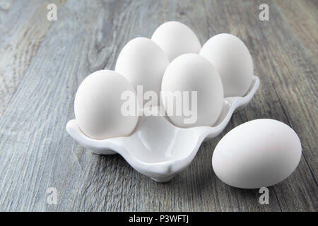 6 grands oeufs blancs sur un plat de céramique blanche Banque D'Images