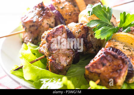 Shish kebab grillé ou brochettes en brochettes avec des feuilles de salade sur l'assiette blanche. Close up. Banque D'Images