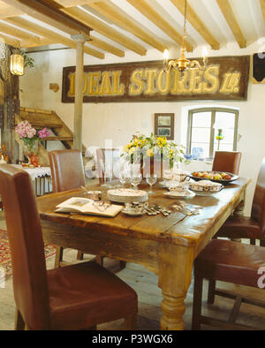 Vieux store se connecter sur mur en pays salle à manger avec des chaises en cuir brun capitonnés et vieille table en bois Banque D'Images