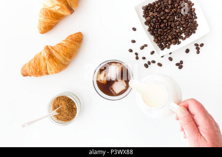 Verser le lait dans la main un verre de café froid. Banque D'Images