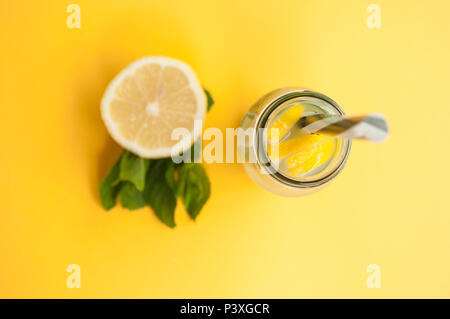 Vue de dessus de pot Mason verre de limonade ou de citrons mojito et menthe sur fond jaune vif. Fraîcheur d'un cocktail. Banque D'Images