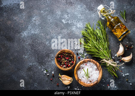 Branches de romarin, sel de mer, poivre, ail et huile d'olive sur une table en pierre. Ingrédients pour la cuisine, vue de dessus, copiez l'espace. Banque D'Images