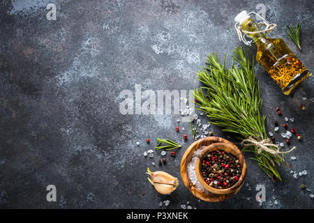 Branches de romarin, sel de mer, poivre, ail et huile d'olive sur une table en pierre. Ingrédients pour la cuisine, vue de dessus, copiez l'espace. Banque D'Images