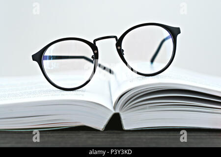Close up of hipster lunettes lunettes pour lire sur un livre ouvert, faible profondeur de champ et selective focus Banque D'Images