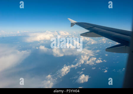 Vue depuis la fenêtre de l'avion des nuages et des terres ci-dessous avec l'aile en vue Banque D'Images