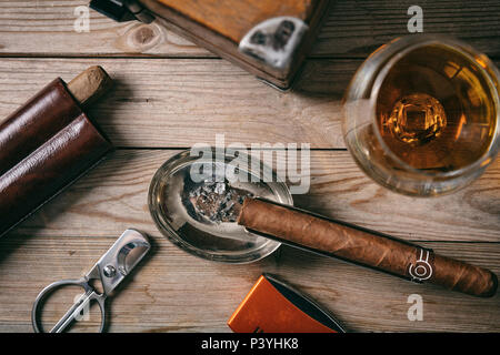 Cigare cubain et un verre de cognac brandy sur fond de bois, haut Vue rapprochée Banque D'Images