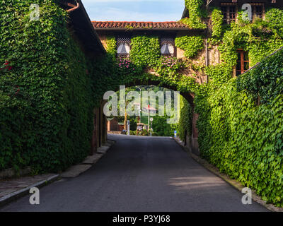 Biella, Italie, 10 juin 2018 - maison de brique, les murs couverts de lierre et d'arche reliant la deuxième partie de la chambre avec road ci-dessous, Italie Banque D'Images