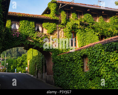 Biella, Italie, 10 juin 2018 - maison ancienne, les murs couverts de lierre et d'arche reliant la deuxième partie de la chambre avec road ci-dessous, Italie Banque D'Images