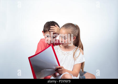 Schoolkids caucasienne, étudier une chatoyante cute girl holding notes, explique un garçon qui a l'air confus et frappe sa main dans ses cheveux sur light background Banque D'Images