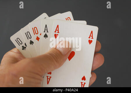 Main de poker avec trois cartes de 10 et deux as - close up sur fond noir Banque D'Images