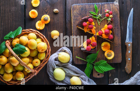 Abricots frais et des morceaux de gâteau au fromage sur une planche de bois brun, vue du dessus Banque D'Images