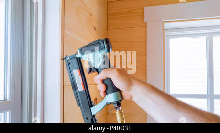 Carpenter brad à l'aide de pistolets à moulures sur windows, encadrement de caisse, Close up sur la main et pistolet Banque D'Images