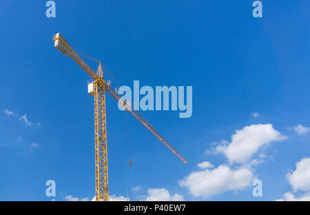 Grue à tour de construction jaune sur fond de ciel bleu. Banque D'Images