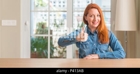 Femme rousse à la maison faisant plaisir Thumbs up geste avec la main. L'expression d'approbation regardant la caméra avec succès. Banque D'Images