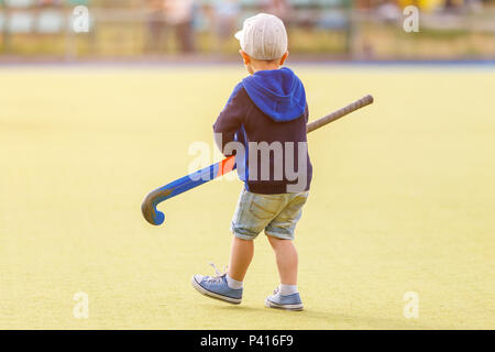 Petit Garçon jouant au hockey avec champ de formation stick sur le champ Banque D'Images