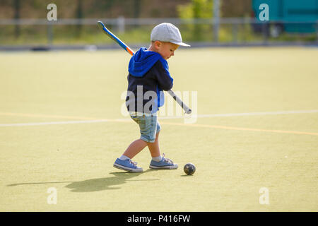 Petit Garçon jouant au hockey avec champ de formation stick sur le champ Banque D'Images