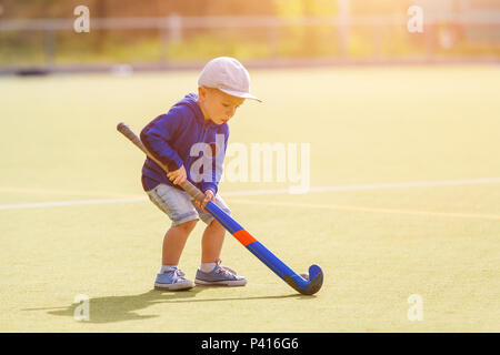 Petit Garçon jouant au hockey avec champ de formation stick sur le champ Banque D'Images