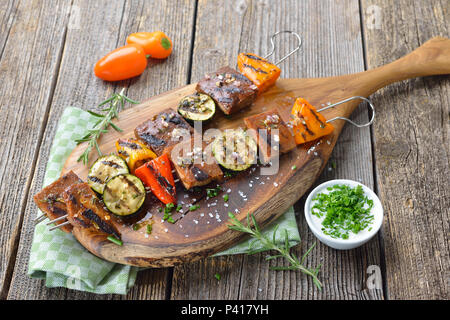 Végétalien : brochettes grillées avec un mélange de légumes et le seitan servi sur une planche à découper en bois avec une sauce de soja aux herbes Banque D'Images