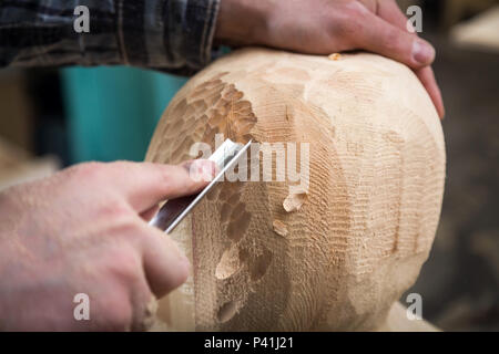 Portrait jeune homme carpenter dans un vêtement de travail bp sur la tête d'un homme avec un arbre , à l'aide d'un burin dans l'atelier, autour d'un lot d'outils pour le travail Banque D'Images