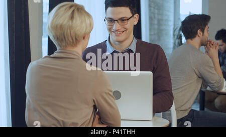 Deux young businesspeople using laptop in lobby of modern office Banque D'Images